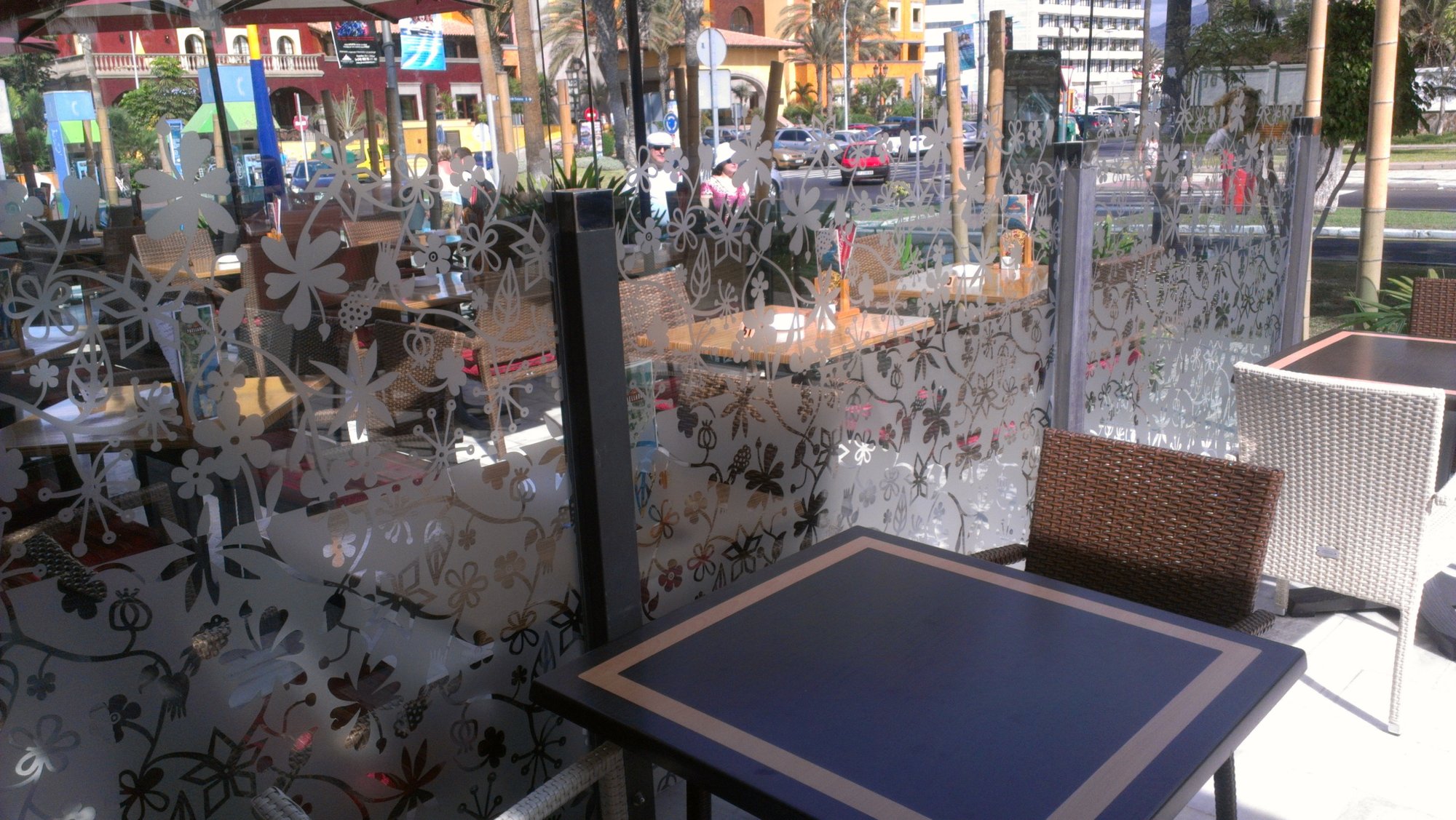 Glass terrace screen sandblasted with a pattern of flowers and leaves around outdoor tables