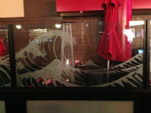 Large wave pattern sandblasted into a glass balustrade screen, seen from another angle