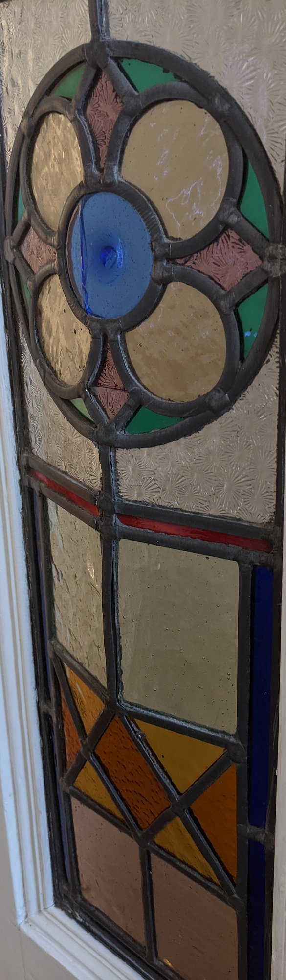 Leaded door panel with a cracked blue roundel, showing glass in need of restoration