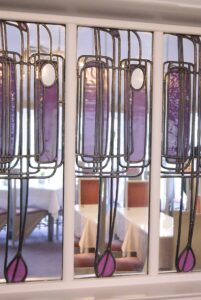 Tall purple leaded glass panels with long stems and rosebud shapes at the Willow Tea Rooms, photographed in 2013